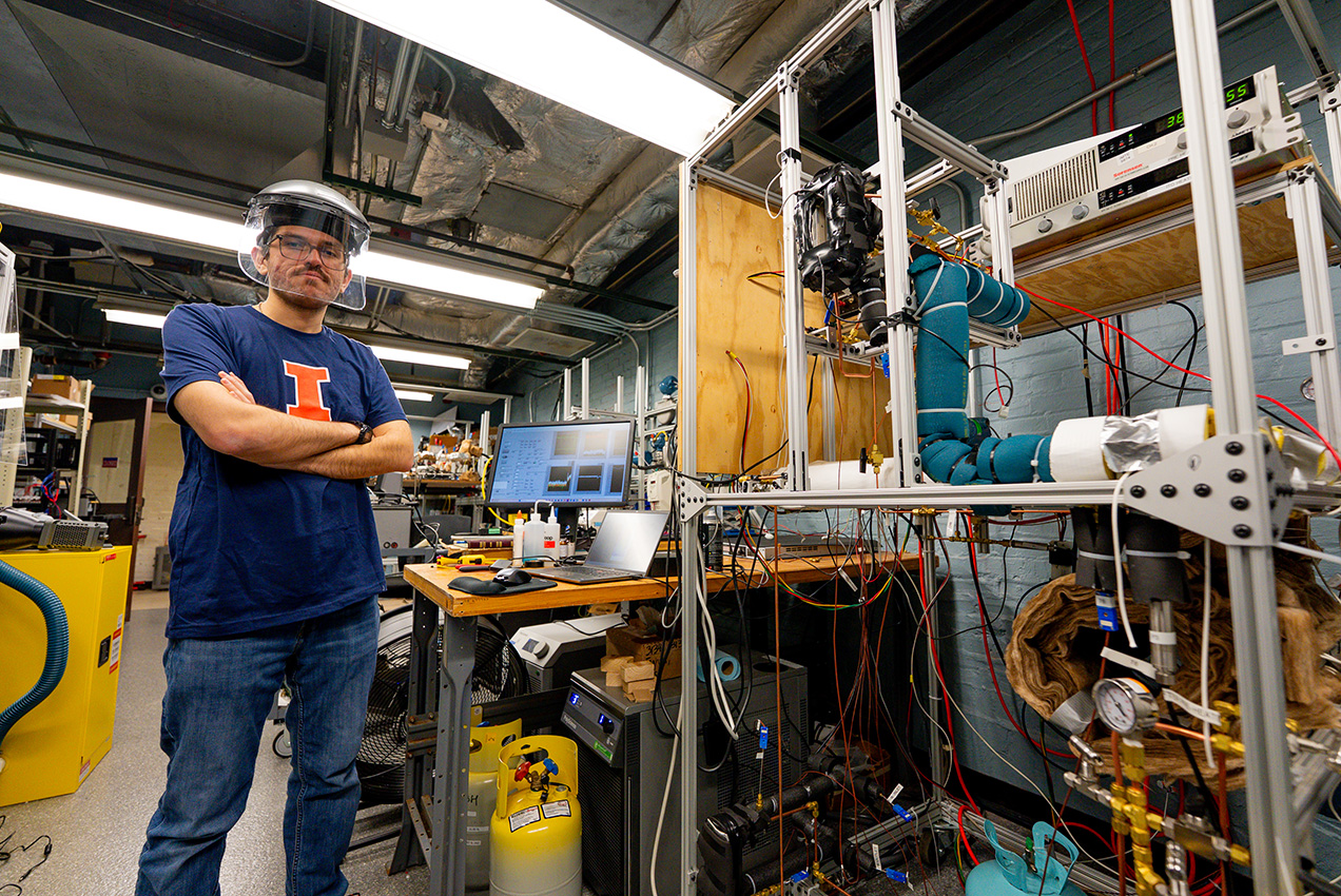male student standing at equipment with his arms crossed